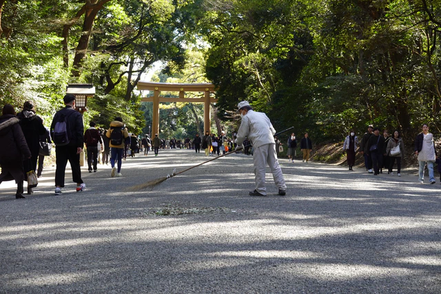 A groundskeeper sweeping the gravel path at Meiji Shrine.