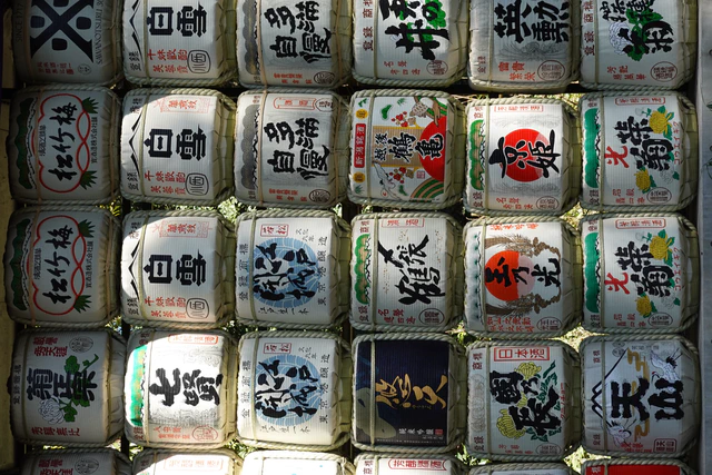 Rows of ornate sake barrels stacked along a shrine path.